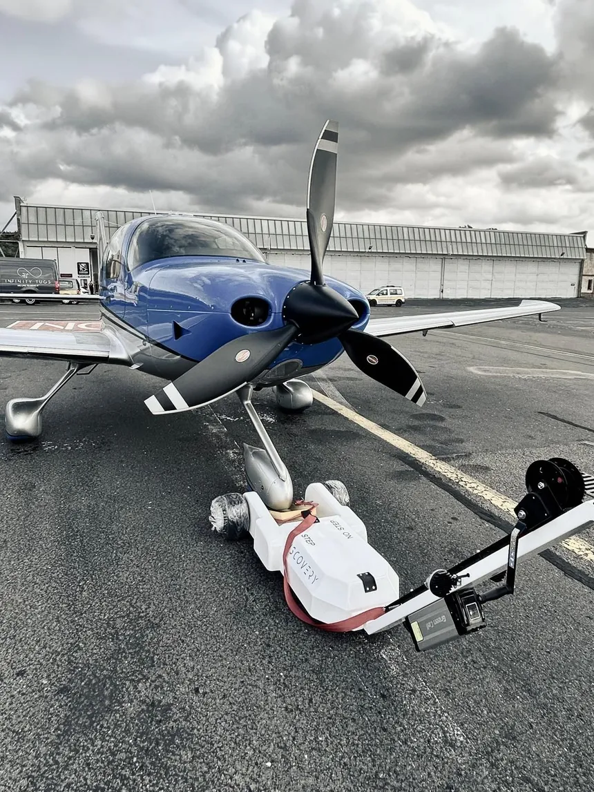 DISCOVERY electric aircraft tug positioned at the nose wheel of a single-engine airplane